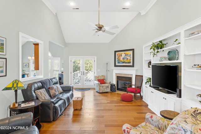 living room featuring a tiled fireplace, hardwood / wood-style floors, french doors, high vaulted ceiling, and ceiling fan