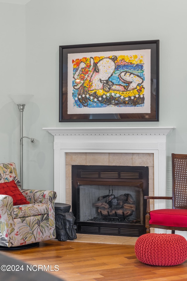 interior details with wood-type flooring and a tile fireplace