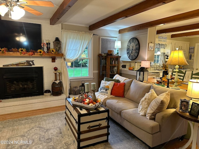 living room featuring beam ceiling, ceiling fan, hardwood / wood-style flooring, and a fireplace