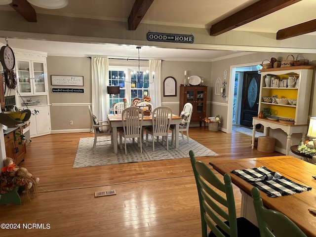 dining space with ornamental molding, hardwood / wood-style floors, beamed ceiling, and a chandelier