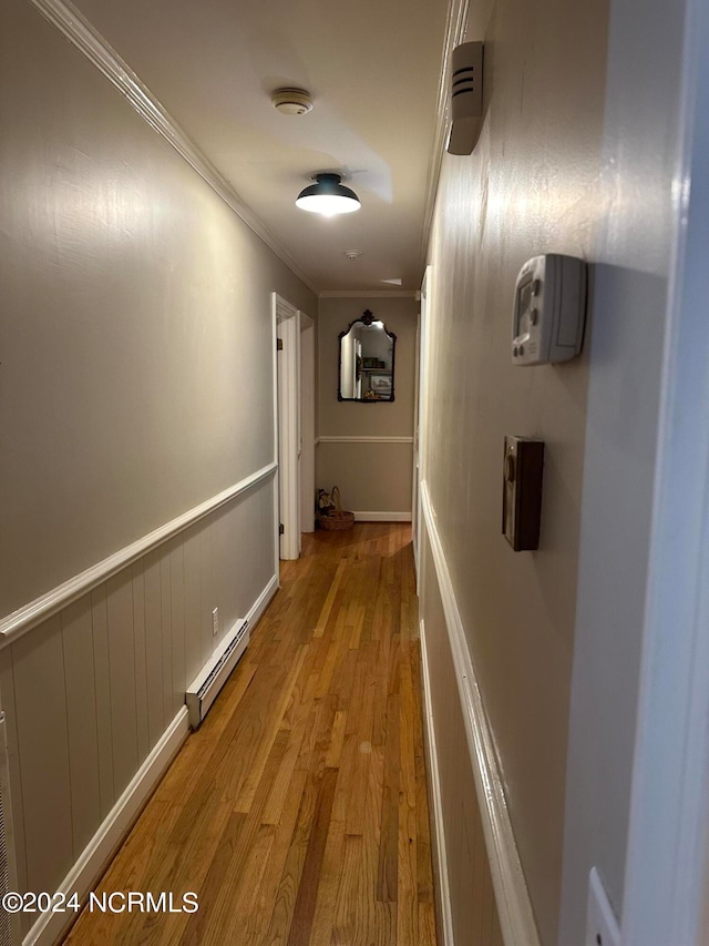 corridor featuring a baseboard radiator, light wood-type flooring, and crown molding