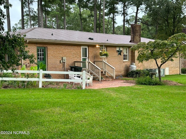 rear view of property featuring a lawn and a patio area