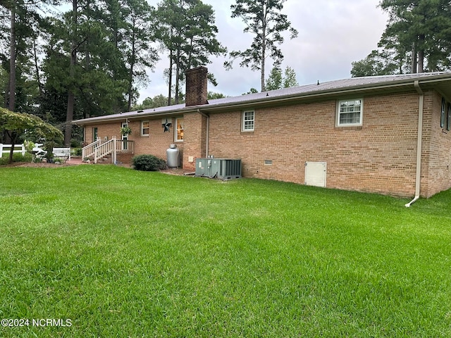 back of house with a lawn and central air condition unit