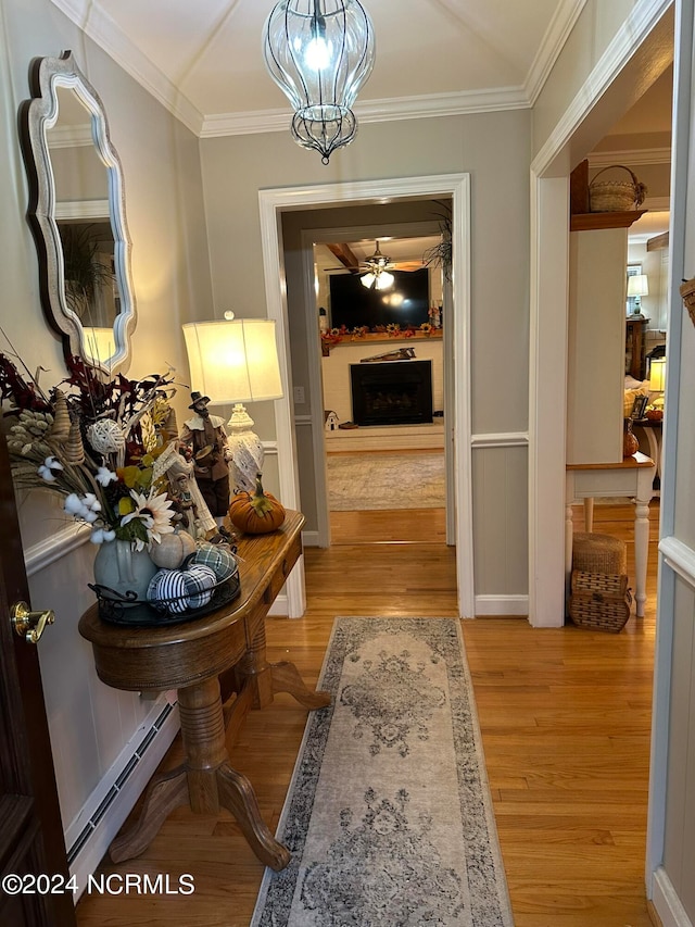 corridor with crown molding, light hardwood / wood-style floors, a baseboard heating unit, and a chandelier