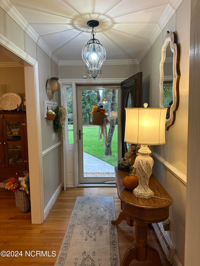 entrance foyer featuring an inviting chandelier, light wood-type flooring, crown molding, and baseboard heating