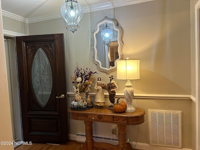 foyer featuring hardwood / wood-style flooring, ornamental molding, and a baseboard heating unit