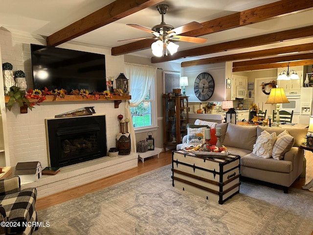 living room with a brick fireplace, beam ceiling, hardwood / wood-style floors, and ceiling fan