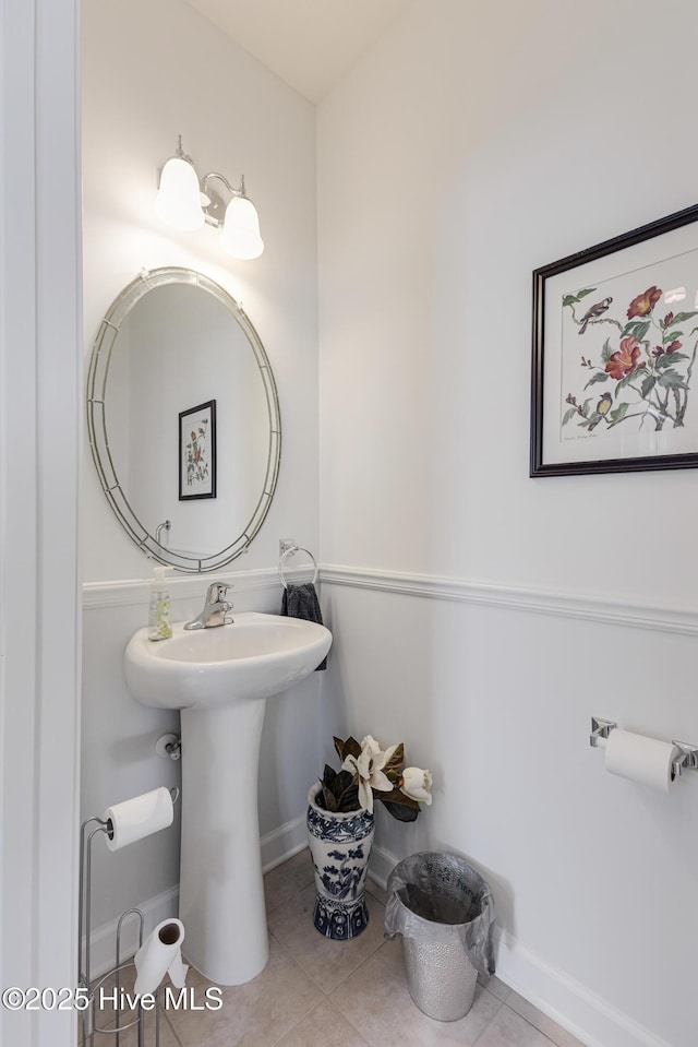 bathroom featuring baseboards, a sink, and tile patterned floors