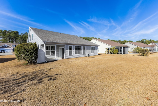 rear view of property with a lawn and roof with shingles