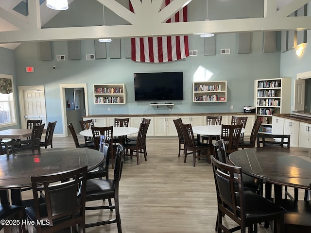 dining area featuring light wood-type flooring, high vaulted ceiling, and visible vents