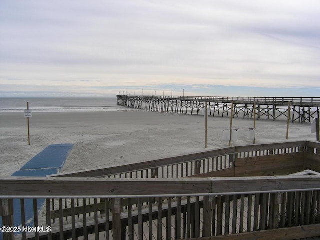 wooden deck featuring a beach view and a water view