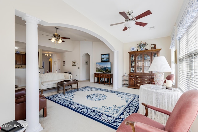 living area featuring carpet floors, lofted ceiling, visible vents, a ceiling fan, and ornate columns