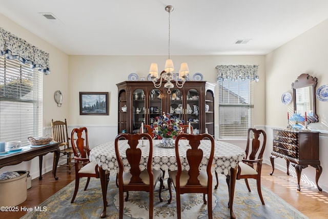 dining room with wood-type flooring, a wealth of natural light, and a chandelier