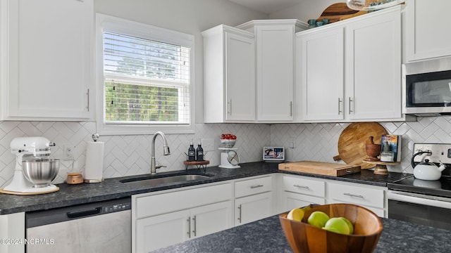 kitchen featuring white cabinetry, backsplash, stainless steel appliances, dark stone counters, and sink