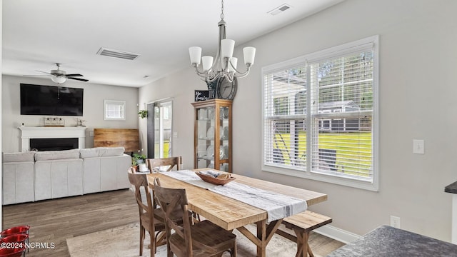 dining space with ceiling fan with notable chandelier and hardwood / wood-style flooring