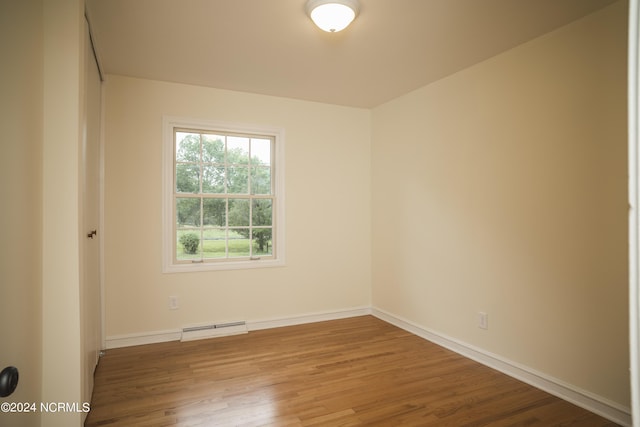 spare room with baseboards, baseboard heating, and wood finished floors