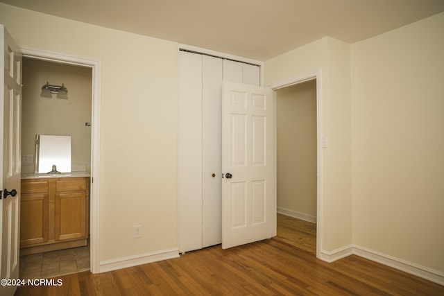 unfurnished bedroom with a closet, wood finished floors, and baseboards