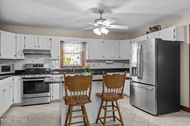 kitchen featuring ceiling fan, appliances with stainless steel finishes, white cabinetry, and a breakfast bar area