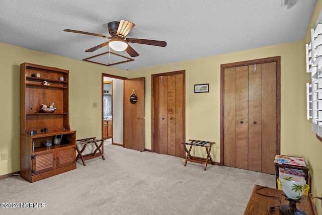 miscellaneous room with ceiling fan, light colored carpet, and a textured ceiling