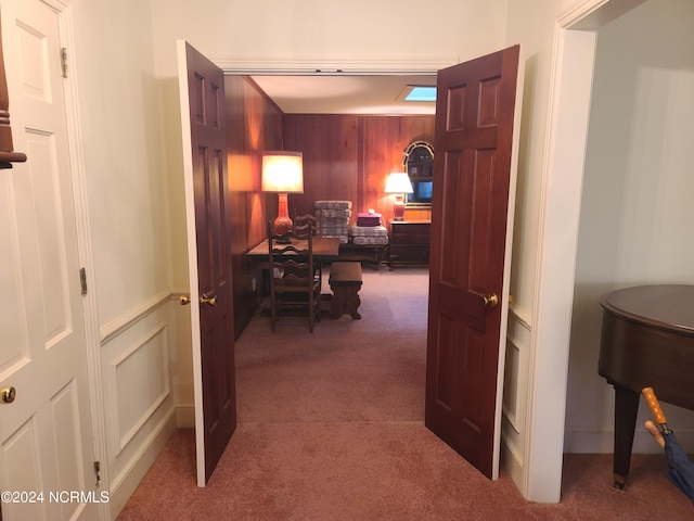 hallway with carpet flooring and wooden walls