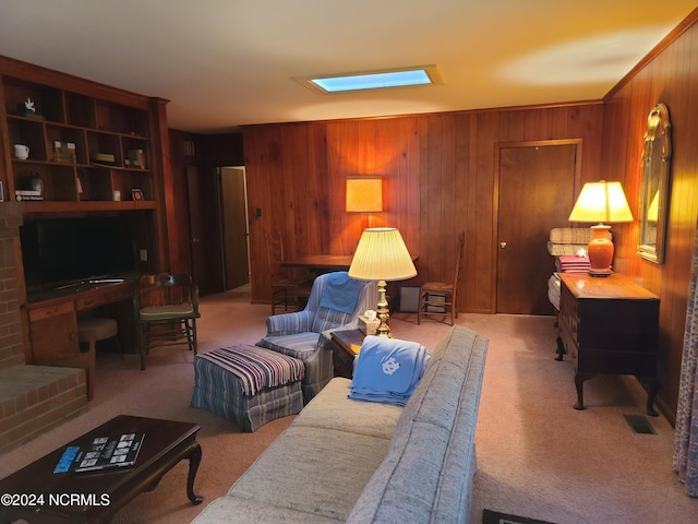 living room with wood walls, crown molding, light colored carpet, and a brick fireplace