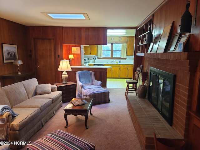 living room featuring a fireplace, light carpet, sink, and wood walls