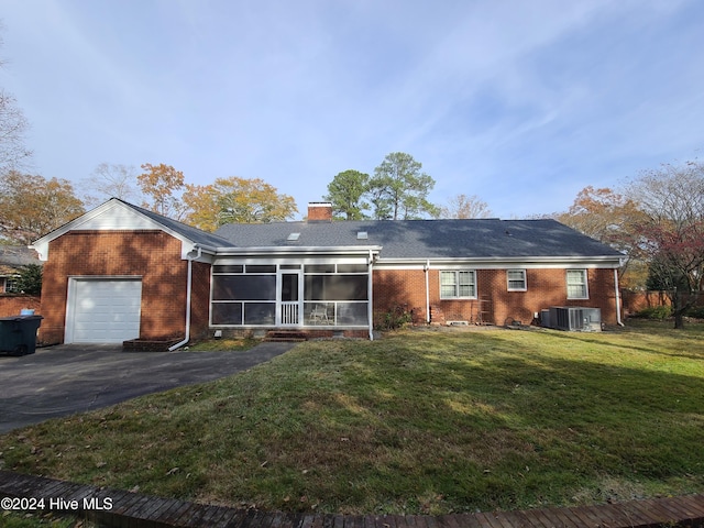 view of front of home with a front yard, a sunroom, a garage, and central air condition unit