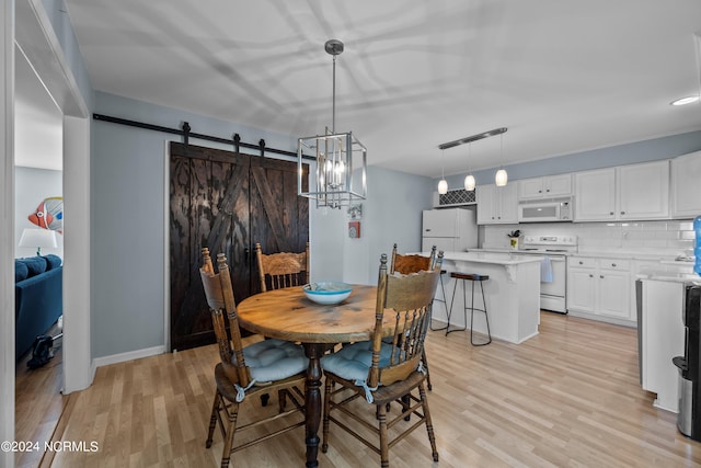 dining area featuring a barn door, a chandelier, and light hardwood / wood-style floors