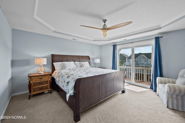 carpeted bedroom with a textured ceiling, ceiling fan, a tray ceiling, and access to outside