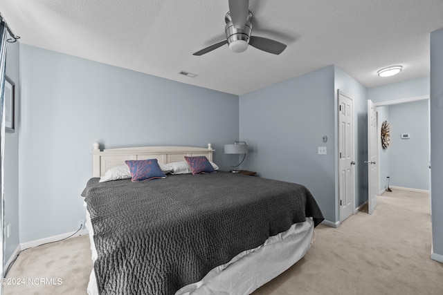 bedroom featuring a textured ceiling, a closet, ceiling fan, and light carpet