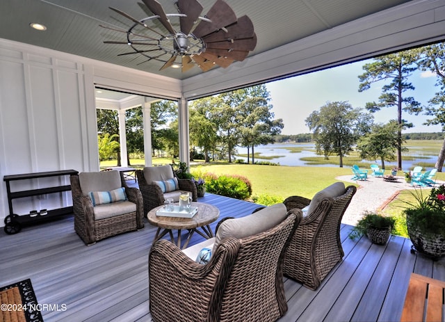 deck featuring a water view, ceiling fan, and a lawn