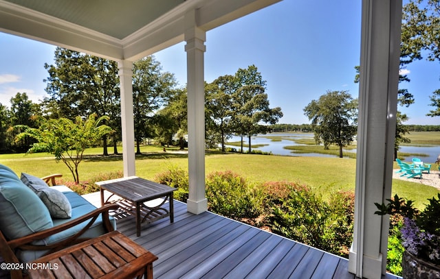 wooden deck with a water view and a lawn