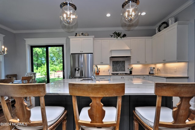 kitchen featuring pendant lighting, white cabinets, decorative backsplash, stainless steel fridge, and a chandelier