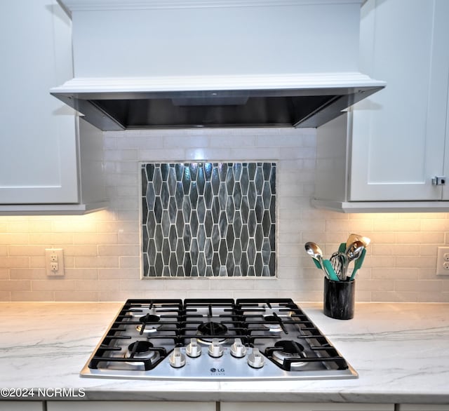 details featuring stainless steel gas stovetop, light stone countertops, and decorative backsplash