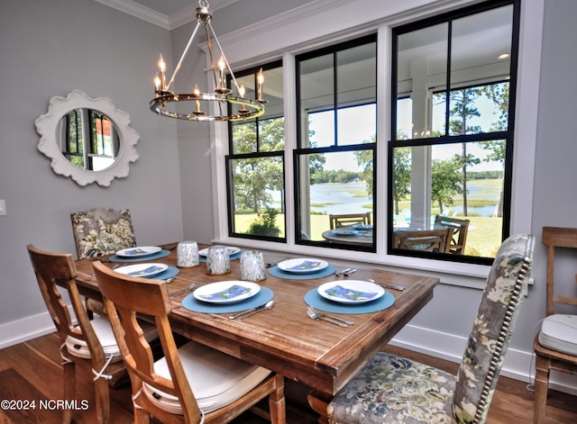 dining area with hardwood / wood-style flooring, a healthy amount of sunlight, crown molding, and an inviting chandelier