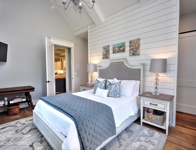 bedroom featuring hardwood / wood-style flooring, vaulted ceiling with beams, ceiling fan, and ensuite bath