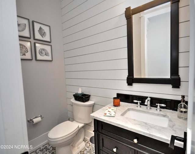 bathroom featuring wooden walls, tile patterned flooring, vanity, and toilet