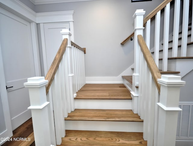 stairs with hardwood / wood-style floors and crown molding