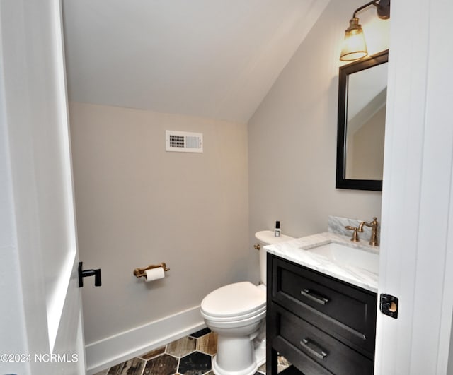 bathroom with tile patterned floors, vanity, toilet, and vaulted ceiling