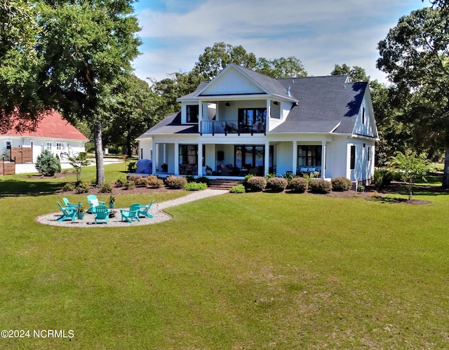 view of front of house with a fire pit, a balcony, and a front lawn