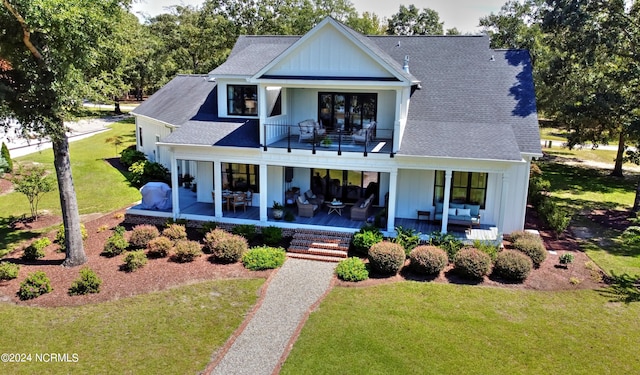 rear view of house with a lawn and a balcony