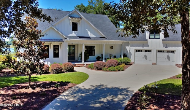 modern inspired farmhouse featuring a porch, a garage, and a front yard