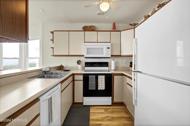 kitchen featuring white appliances, light wood finished floors, light countertops, open shelves, and a sink