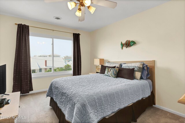 carpeted bedroom featuring a ceiling fan, visible vents, and baseboards