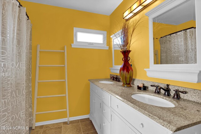 full bath with double vanity, a sink, and baseboards