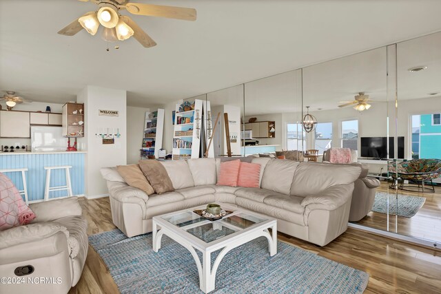 living room featuring ceiling fan with notable chandelier and wood finished floors