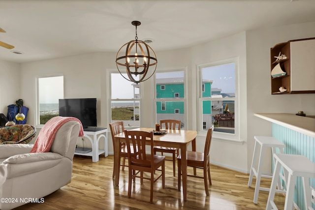 dining area with baseboards, light wood-type flooring, and an inviting chandelier