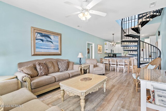 living room featuring ceiling fan with notable chandelier and light hardwood / wood-style flooring