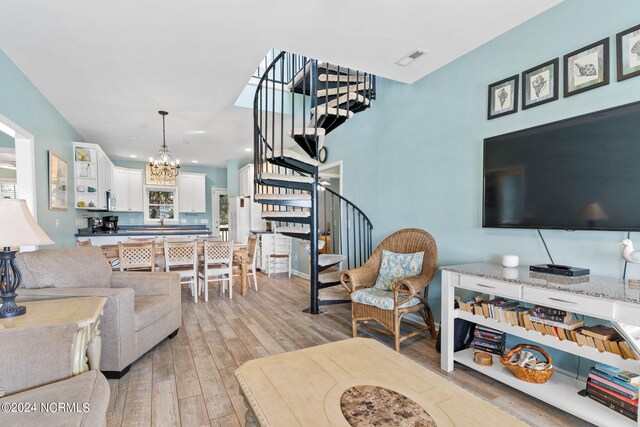 living room featuring an inviting chandelier, light wood-type flooring, and sink