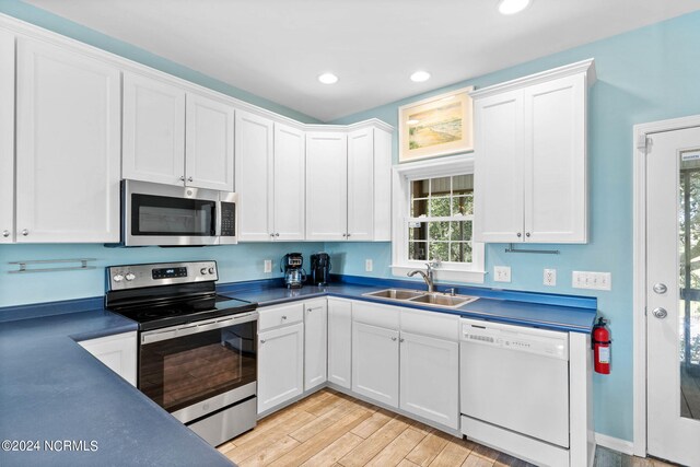 kitchen with light wood-type flooring, sink, stainless steel appliances, and white cabinets